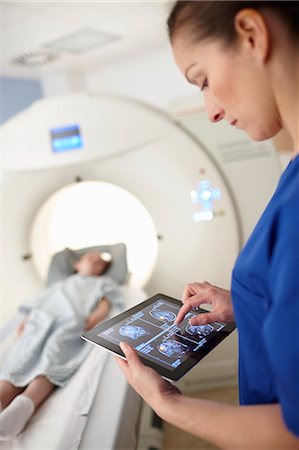 Radiographer looking at brain scan image on digital tablet Fotografie stock - Premium Royalty-Free, Codice: 649-07709924