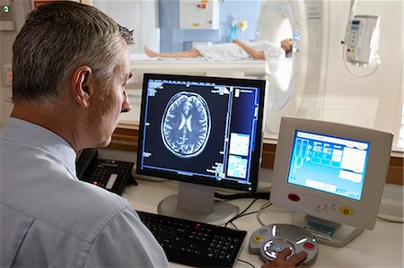 Radiologist looking at brain scan image on computer screen Photographie de stock - Premium Libres de Droits, Code: 649-07709928