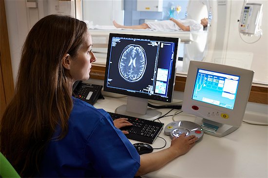 Radiologist looking at brain scan image on computer screen Photographie de stock - Premium Libres de Droits, Le code de l’image : 649-07709929