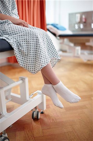 Girl sitting on hospital bed, wearing examination gown Fotografie stock - Premium Royalty-Free, Codice: 649-07709936