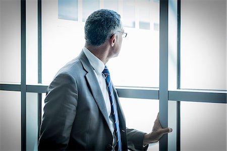 suit man at window - Businessman looking out through glass wall Stock Photo - Premium Royalty-Free, Code: 649-07710045