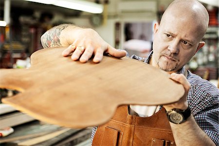 Guitar maker checking wooden guitar shape in workshop Photographie de stock - Premium Libres de Droits, Code: 649-07710266