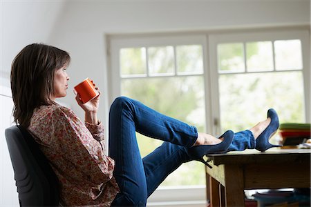 schlürfen - Mature woman with feet on desk, drinking coffee Stockbilder - Premium RF Lizenzfrei, Bildnummer: 649-07710437