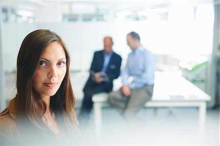 person blurred - Woman posing for camera, businessmen in background Stock Photo - Premium Royalty-Free, Code: 649-07710473