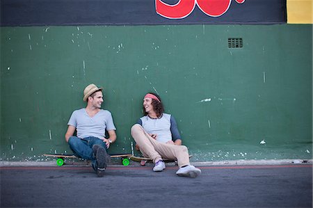 skateboard street - Two adult male friends sitting on skateboards chatting Stock Photo - Premium Royalty-Free, Code: 649-07710517