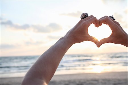 Female hands making heart shape at sunset on beach Stock Photo - Premium Royalty-Free, Code: 649-07710711