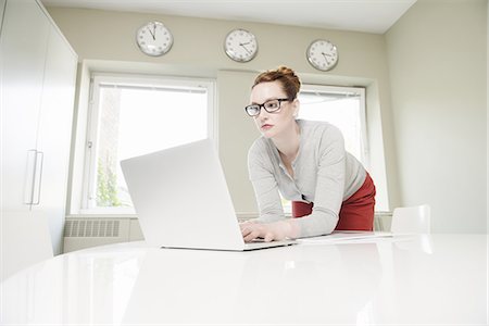 Mid adult businesswoman leaning forward to use laptop Stock Photo - Premium Royalty-Free, Code: 649-07736471