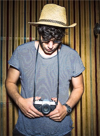 photographer (male) - Portrait of young man looking down at vintage camera Foto de stock - Sin royalties Premium, Código: 649-07736498