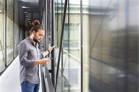 Man using smartphone in corridor Photographie de stock - Premium Libres de Droits, Code: 649-07736608