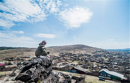 simsearch:649-07063009,k - Young female hiker looking over shoulder on top of mountain rock Stock Photo - Premium Royalty-Free, Code: 649-07736639