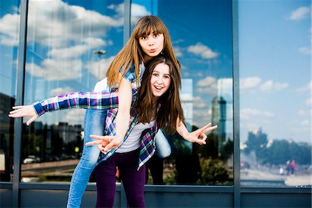 Two young women piggybacking and making peace signs Stock Photo - Premium Royalty-Free, Code: 649-07736847