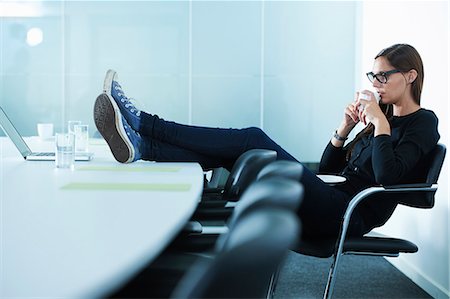 future business - Female office worker drinking coffee with feet up on conference table Stock Photo - Premium Royalty-Free, Code: 649-07736842