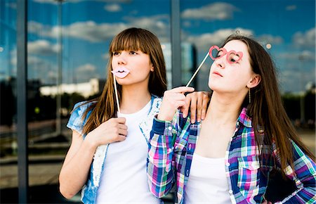 Two young women looking up with lip and spectacles costume masks Photographie de stock - Premium Libres de Droits, Code: 649-07736853