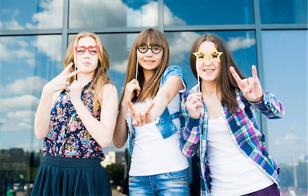 simsearch:649-07436674,k - Portrait of three young women with eyeglasses costume masks and making hand gestures Fotografie stock - Premium Royalty-Free, Codice: 649-07736866