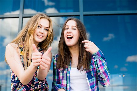 Portrait of two young women making thumbs up in front of glass fronted office Stock Photo - Premium Royalty-Free, Code: 649-07736863