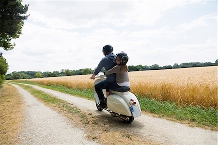 sharing with in family - Rear view of mature man and daughter riding motor scooter along dirt track Photographie de stock - Premium Libres de Droits, Code: 649-07736898