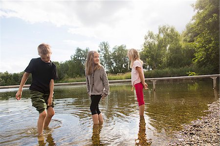 preteen boys smile long hair side - Brother and two sisters paddling in lake Stock Photo - Premium Royalty-Free, Code: 649-07736900