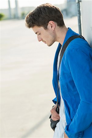 simsearch:649-03566205,k - Serious young man with shoulder bag leaning against wall Stock Photo - Premium Royalty-Free, Code: 649-07736958