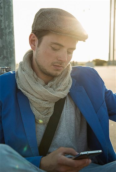 Young man leaning against wall texting on smartphone Stock Photo - Premium Royalty-Free, Image code: 649-07736968