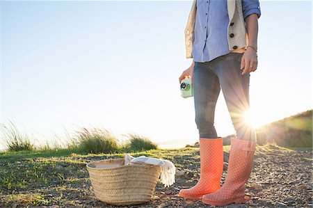 Young woman in wellies standing against sunset Stock Photo - Premium Royalty-Free, Code: 649-07737009