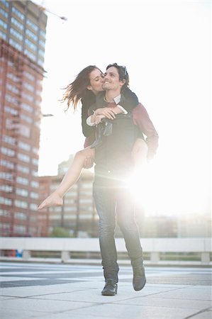 simsearch:649-07560088,k - Mid adult man giving girlfriend piggyback on rooftop parking lot Foto de stock - Sin royalties Premium, Código: 649-07737041