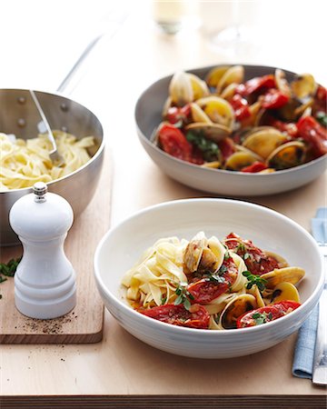 simsearch:614-08120010,k - Bowls of fettucine clams with fresh tomatoes and herb garnish Foto de stock - Sin royalties Premium, Código: 649-07737056