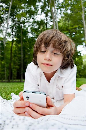 simsearch:614-06442909,k - Boy lying on front reading messages on smartphone Stock Photo - Premium Royalty-Free, Code: 649-07760886