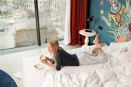 Young woman having a coffee whilst lying on hotel bed Foto de stock - Sin royalties Premium, Código: 649-07760903