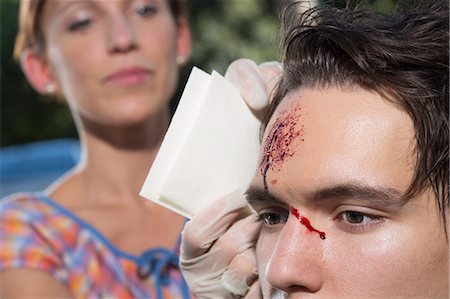 Woman cleaning young man with bleeding forehead Foto de stock - Sin royalties Premium, Código: 649-07760996