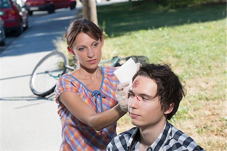 Woman cleaning man with bleeding forehead Foto de stock - Sin royalties Premium, Código: 649-07760997