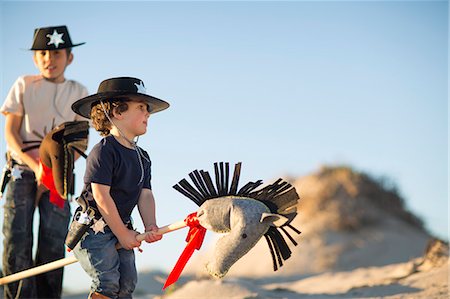 dressed up - Two brothers dressed as cowboys with hobby horses in sand dunes Stock Photo - Premium Royalty-Free, Code: 649-07761107