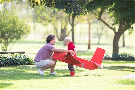 rubber boots - Father crouching to prepare toy airplane for his son in park Stock Photo - Premium Royalty-Free, Code: 649-07761118