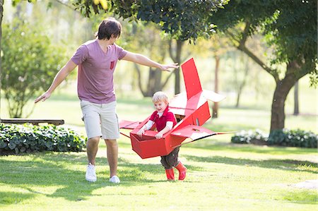 father and son with toy airplane - Father and son running with toy airplane in park Stock Photo - Premium Royalty-Free, Code: 649-07761119