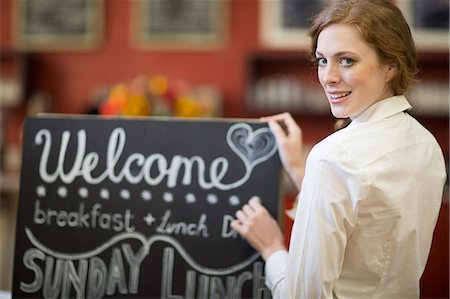 people holding chalkboards in pictures - Portrait of waitress chalking menu on blackboard in restaurant Stock Photo - Premium Royalty-Free, Code: 649-07761228