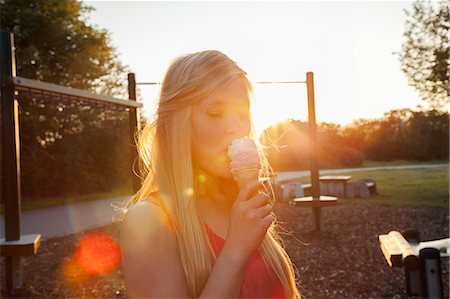 simsearch:649-07905189,k - Young woman eating ice cream cone in park at sunset Photographie de stock - Premium Libres de Droits, Code: 649-07804005