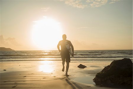 Mature man, running towards sea, holding surf board Photographie de stock - Premium Libres de Droits, Code: 649-07804075