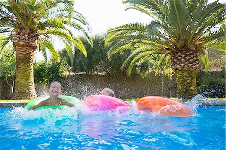 simsearch:614-09057250,k - Three children splashing on inflatable rings in garden swimming pool Fotografie stock - Premium Royalty-Free, Codice: 649-07804164