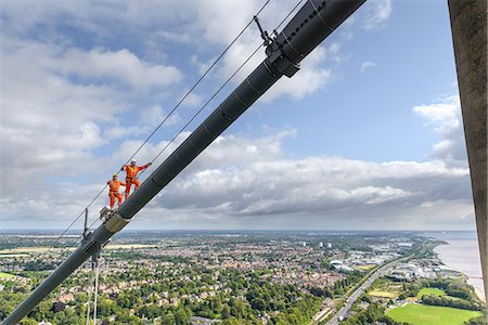 Bridge workers walking on cable of suspension bridge. The Humber Bridge, UK was built in 1981 and at the time was the world's largest single-span suspension bridge Photographie de stock - Premium Libres de Droits, Code: 649-07804229