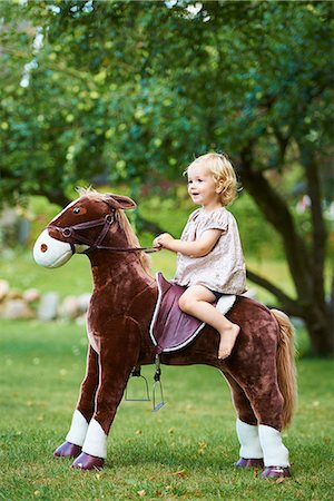 simsearch:649-08084693,k - Portrait of female toddler riding toy horse in garden Foto de stock - Royalty Free Premium, Número: 649-07804292