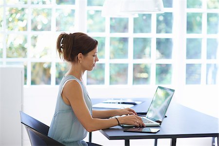 side by side - Mid adult woman working on laptop in dining room Stock Photo - Premium Royalty-Free, Code: 649-07804300