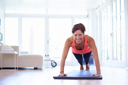 Mid adult woman doing press ups in living room Stock Photo - Premium Royalty-Free, Code: 649-07804315