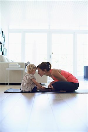 Mid adult mother and toddler daughter practicing lotus position in living room Stock Photo - Premium Royalty-Free, Code: 649-07804310