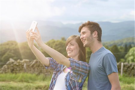 Young couple taking self portrait on mobile phone in countryside under sunny sky Stockbilder - Premium RF Lizenzfrei, Bildnummer: 649-07804416