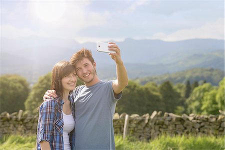 simsearch:649-07280960,k - Young couple taking self portrait on mobile phone in countryside under sunny sky Foto de stock - Sin royalties Premium, Código: 649-07804417