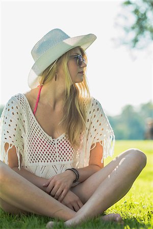 Young woman wearing white sunhat sitting cross legged Photographie de stock - Premium Libres de Droits, Code: 649-07804704