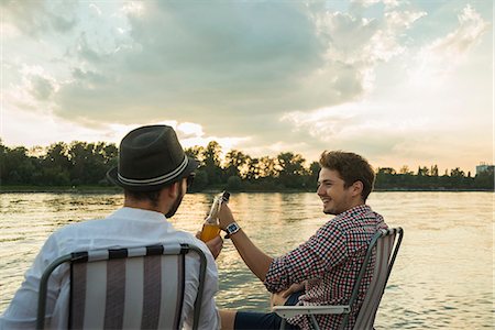 simsearch:649-07804732,k - Young men toasting with beer bottles by lake Foto de stock - Sin royalties Premium, Código: 649-07804744