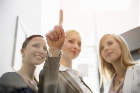 female coworker - Businesswomen looking and pointing on glass Stock Photo - Premium Royalty-Free, Code: 649-07804767