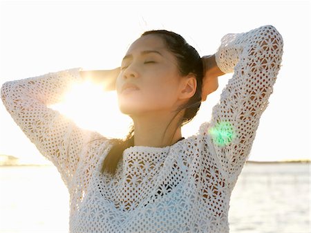 Portrait of young woman on beach with eyes closed and hands on head, Port Melbourne, Melbourne, Victoria, Australia Stock Photo - Premium Royalty-Free, Code: 649-07804942