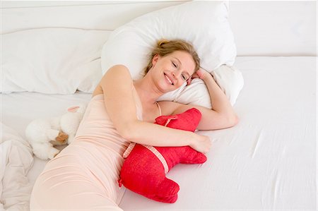 soft toy bed - Mid adult woman lying on bed holding soft toy Photographie de stock - Premium Libres de Droits, Code: 649-07805127