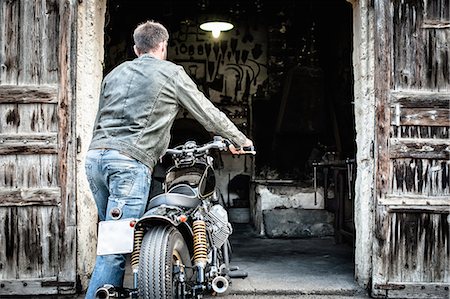 simsearch:649-07803230,k - Mid adult man pushing motorcycle into barn Photographie de stock - Premium Libres de Droits, Code: 649-07803229